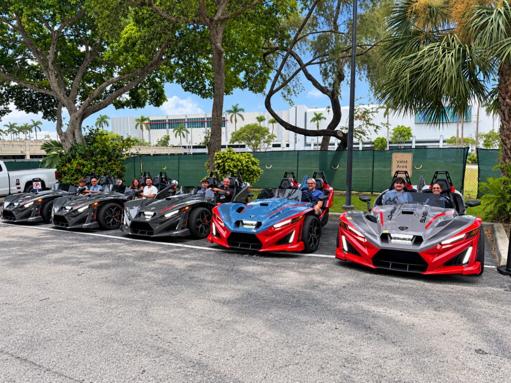 Polaris Slingshots parked in a row under palm trees