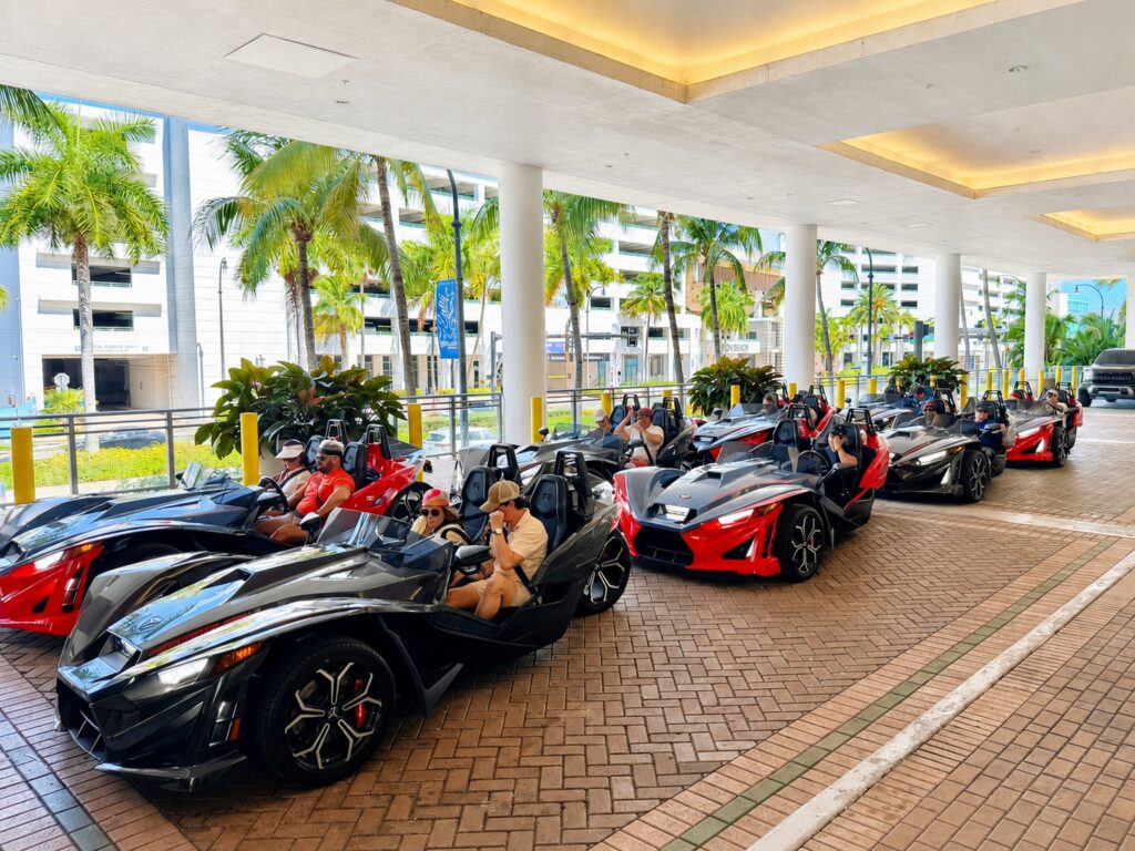 A line of black and red Polaris Slingshots parked at the pickup location