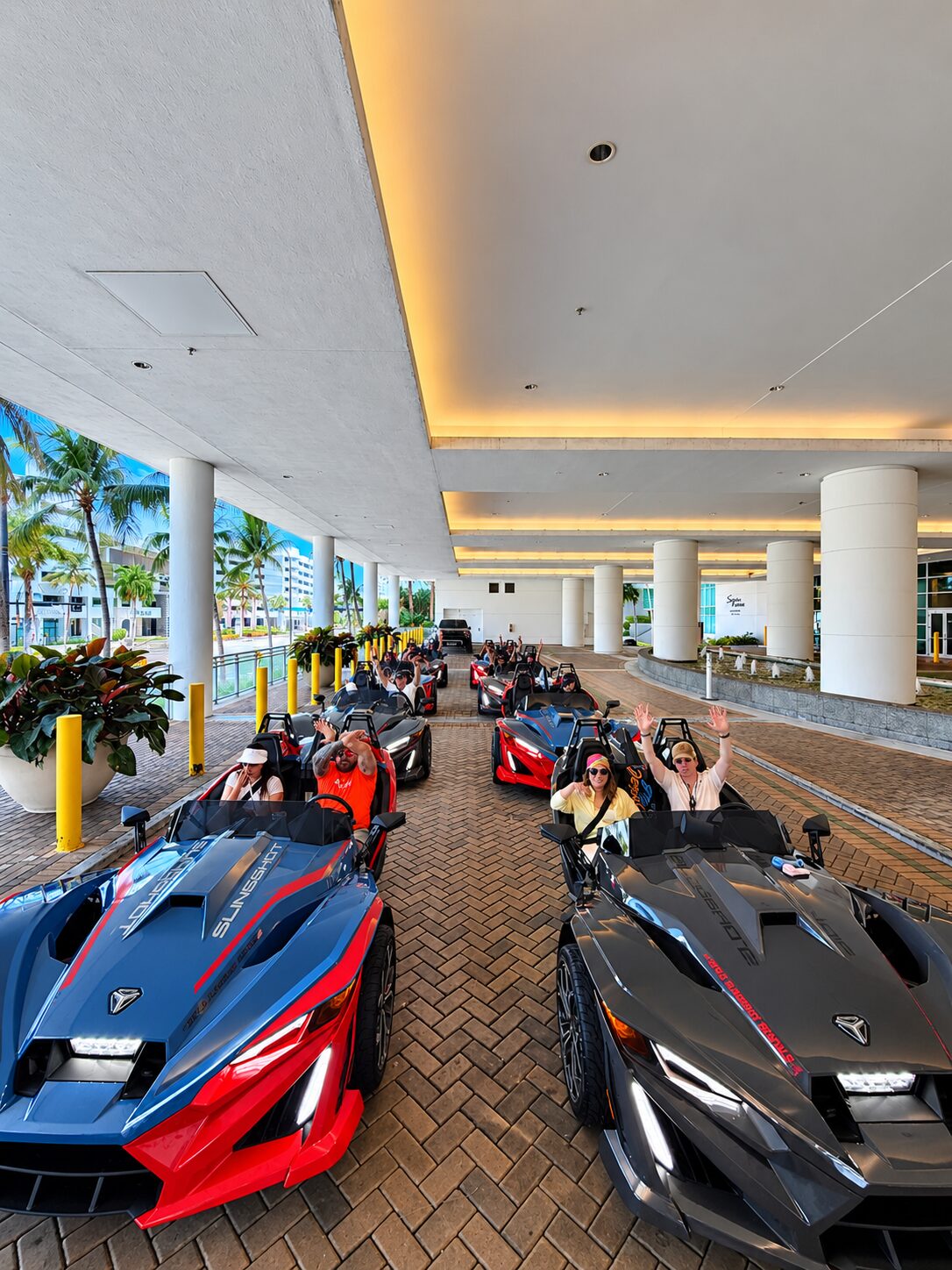 Riders raising their hands in a convoy of Polaris Slingshots